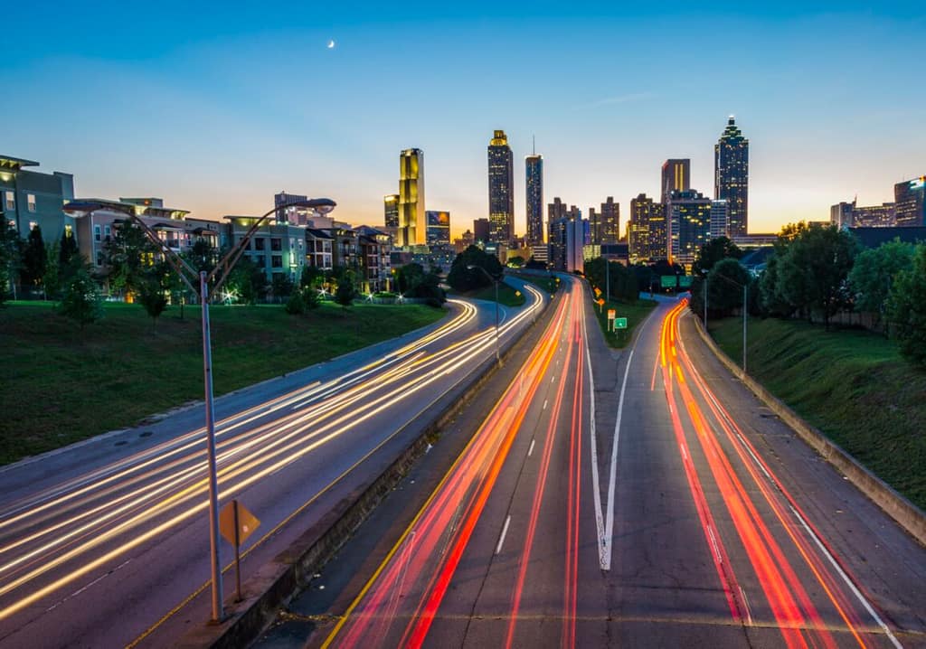 Light trails on a freeway leading into the Atlanta skyline at dusk