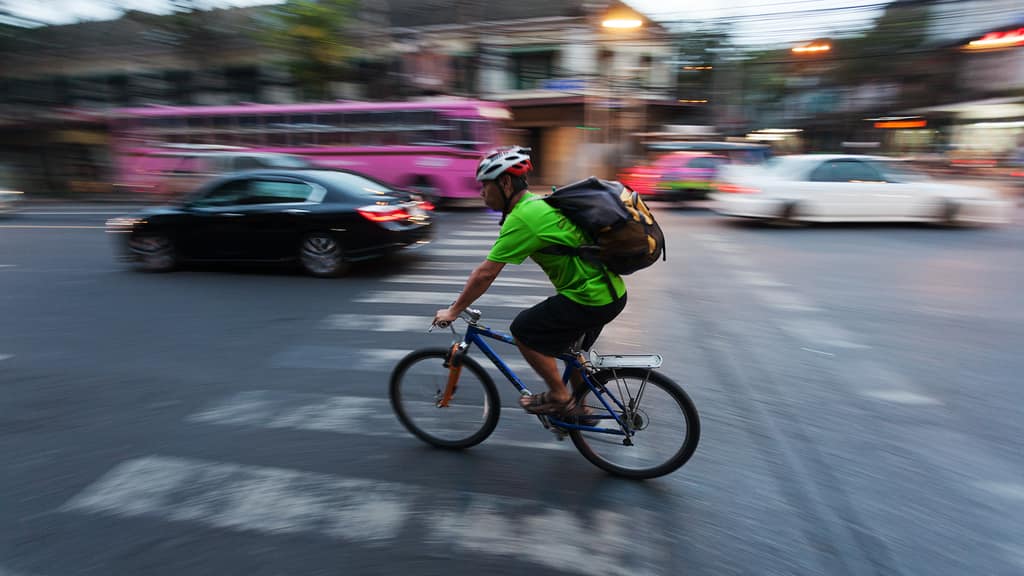 A cyclist riding quickly around a corner in city traffic